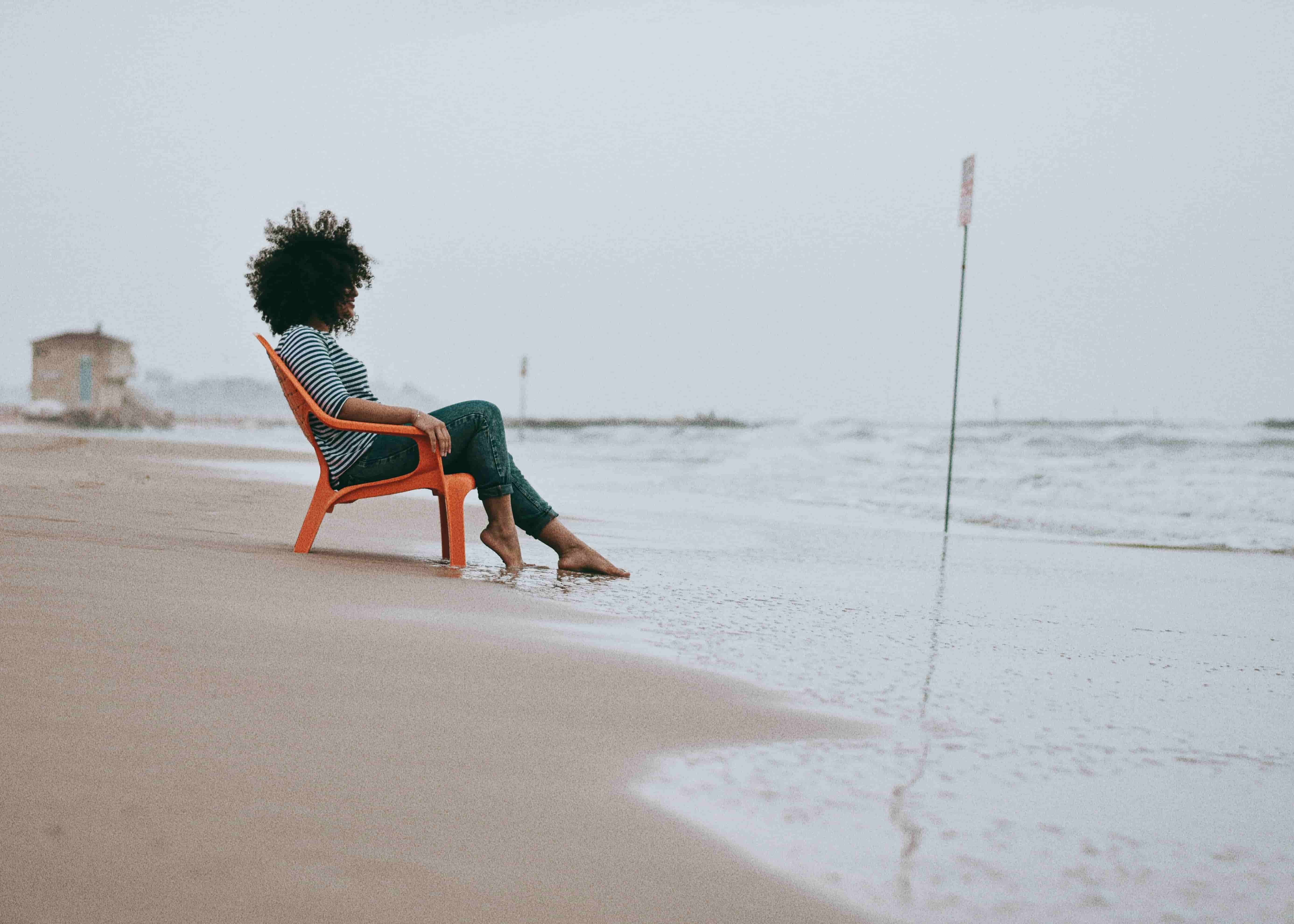 Woman seated at water's edge in quiet reflection